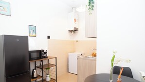 Une cuisine compacte équipée d’un réfrigérateur, d’un four à micro-ondes, d’une machine à café et d’un petit évier.