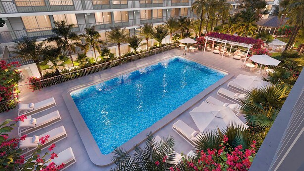 Un hotel con piscina en la azotea, palmeras y sillones de descanso.