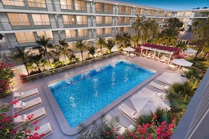 A hotel with a rooftop pool, multiple balconies, and lush landscaping. - Modern Family Studio - 6 mins from Disney, Pool + Free Parking (Kissimmee)