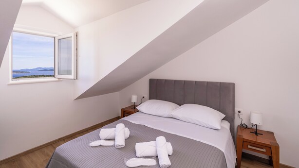 Een slaapkamer met een bed, twee nachtkastjes en een raam met uitzicht.