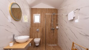 Een moderne badkamer met een groot ovaal wastafel, een toilet, een douche met glazen wanden en een houten wastafelmeubel.