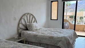 A bedroom with two beds, a large window, and a view of the outside.