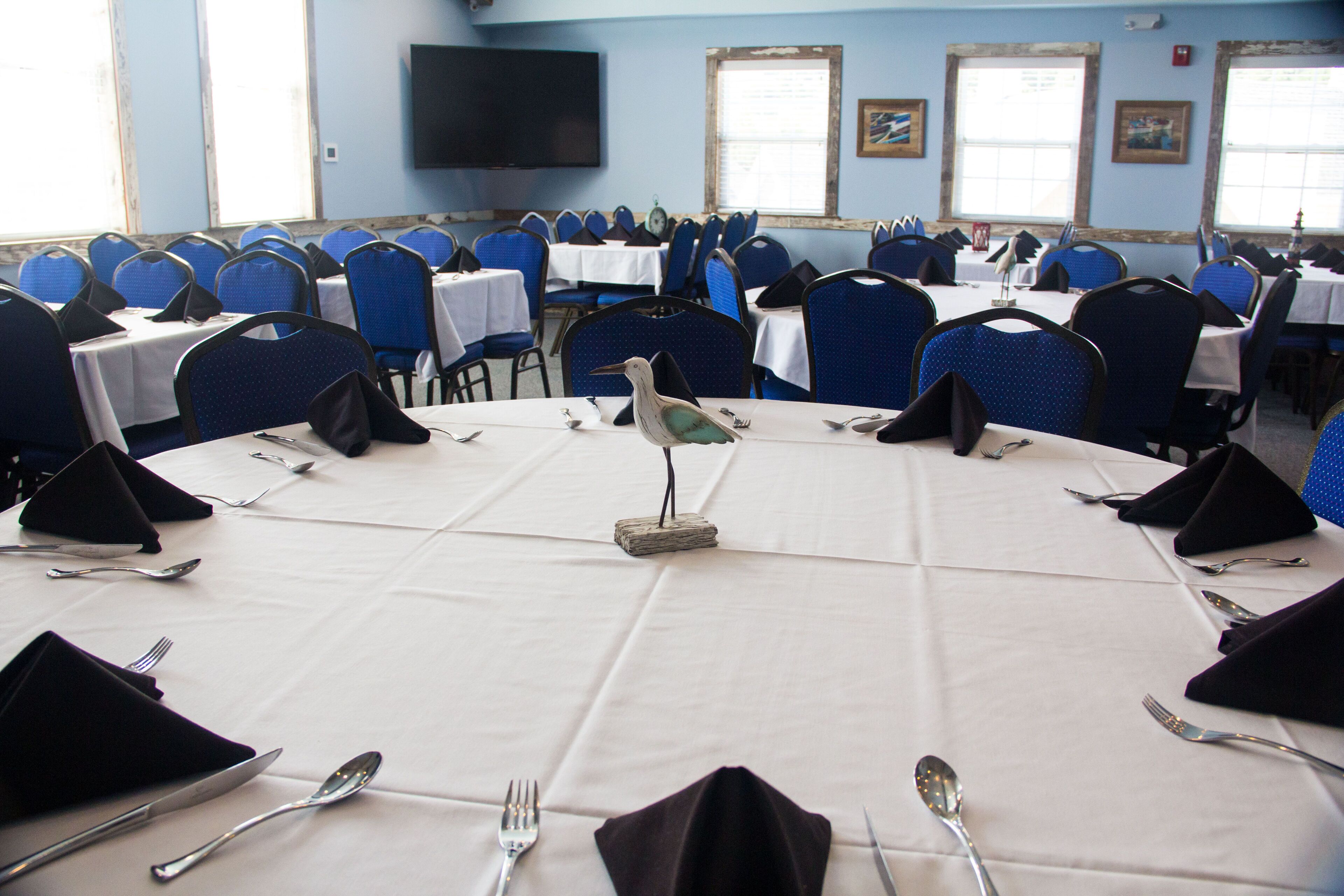 Une salle de conférence avec des tables rondes, des chaises bleues et des nappes blanches.