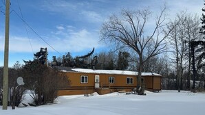 Una casa de dos pisos con techo nevado y un pequeño porche.