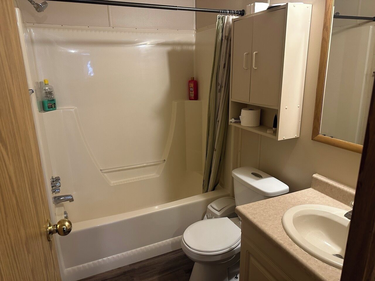 A bathroom with a bathtub, toilet, sink, and a cabinet with toiletries.