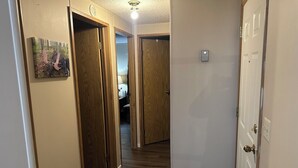 Un pasillo con puertas de madera, una lámpara en el techo y un timbre.