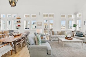 A spacious living room with a wooden dining table, grey sofas, and a white coffee table. - Red White and Saguaro 246 DEW (Port Aransas)