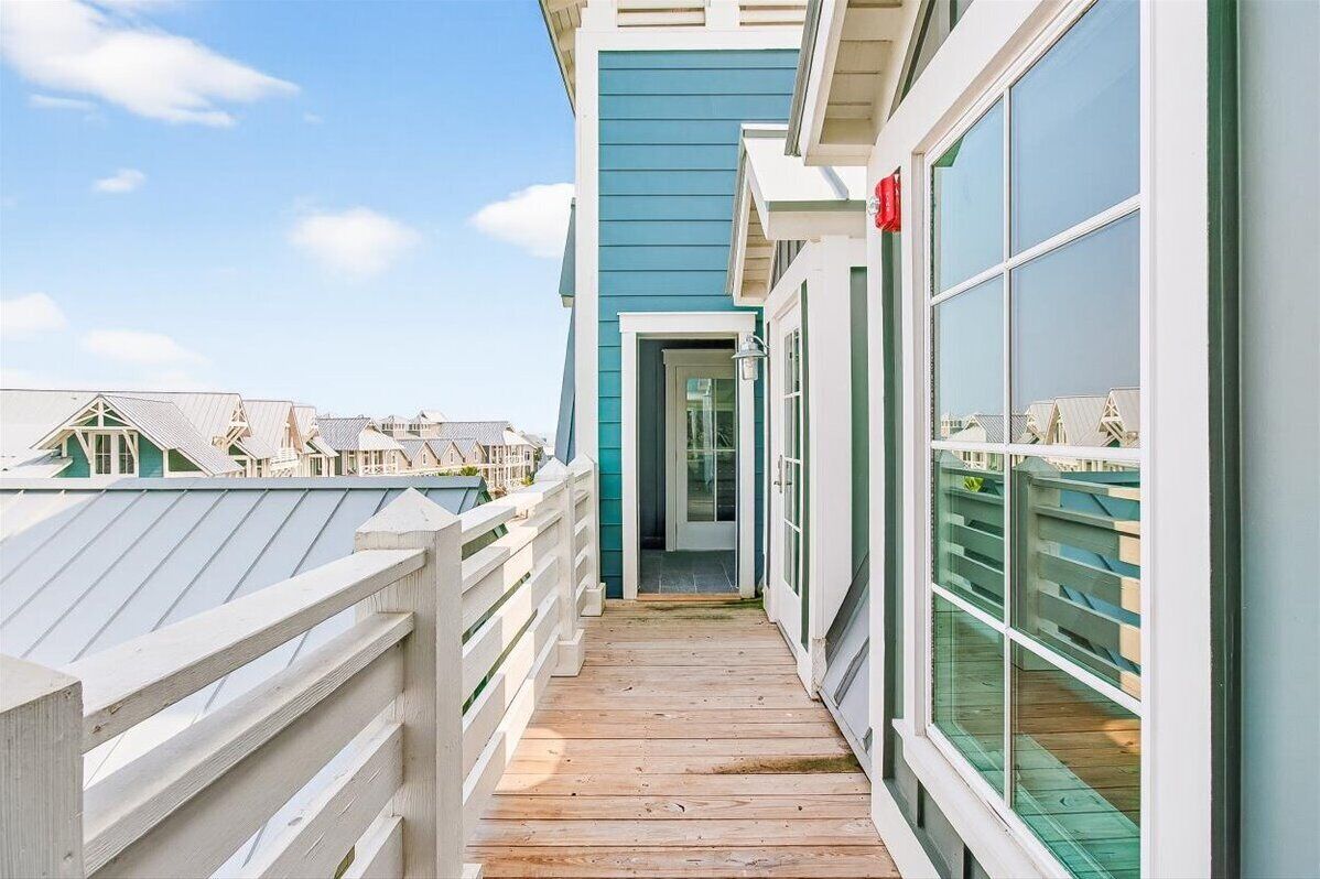 A wooden deck leading to a building with large windows and a door.