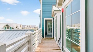 Una terraza de madera que conduce a un edificio con ventanas grandes y una puerta.