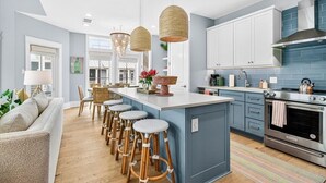 Una cocina moderna con una isla central, taburetes de bar y un comedor.