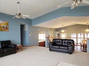 A living room with a black leather sofa, a wooden bench, and a ceiling fan. - 7 Bedroom - 5 Bath Lakefront (Climax Springs)