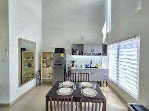Eine kleine Küche mit Kühlschrank, Mikrowelle und Kaffeemaschine. Ein Esstisch ist mit Tellern und Gläsern gedeckt.