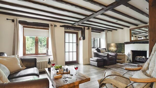A spacious living room with a wooden coffee table, leather sofas, and a fireplace. - Poppy Cottage - Coniston - Pass the Keys (Coniston)