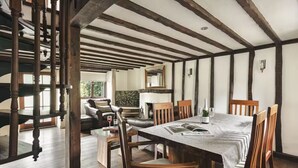 A dining area with a large wooden table, chairs, and a view of a kitchen and living room in the background. - Poppy Cottage - Coniston - Pass the Keys (Coniston)