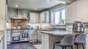 Eine moderne Küche mit Edelstahlgeräten, Granit-Arbeitsplatten und einer großen Kochinsel mit Barhocker.