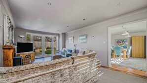 Ein geräumiges Wohnzimmer mit großem Sofa, Flachbildfernseher und Essbereich mit Holztisch und Stühlen.