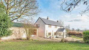 A two-story house with a sloped roof, a front porch, and a garden area. - Spacious 4-Bed in Peaceful Market Drayton - Pass the Keys (Lockleywood)