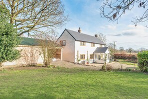 Ein zweistöckiges Haus mit einem geneigten Dach, einer Veranda und einem Garten.