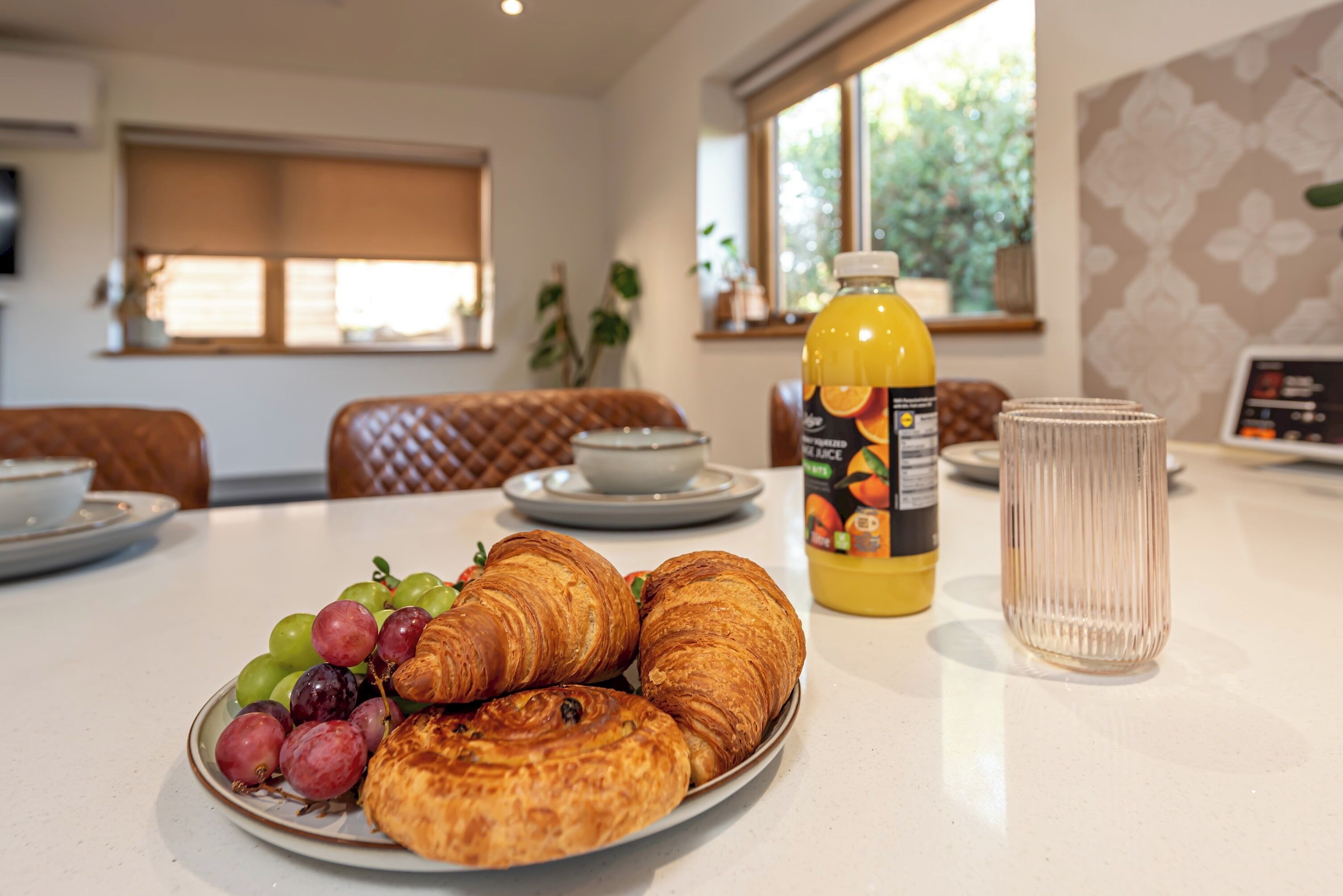 Colazione con croissant, uva e una bottiglia di succo su un tavolo.