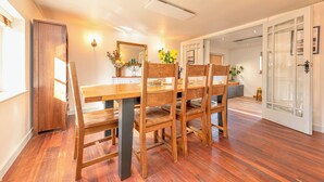 A dining area with a wooden table and chairs, a mirror, and a vase with flowers. - Spacious 4-Bed in Peaceful Market Drayton - Pass the Keys (Lockleywood)