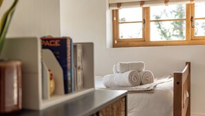 A neatly made bed with rolled towels, a wooden headboard, and a window with a view of trees. - Spacious 4-Bed in Peaceful Market Drayton - Pass the Keys (Lockleywood)