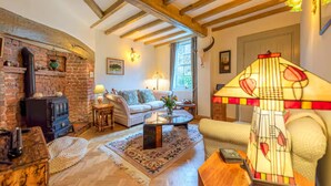 Una sala de estar acogedora con chimenea, un sofá, una mesa de centro y una lámpara.