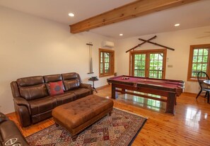 A room with a pool table, leather sofa, ottoman, and a patterned rug. - Game Room, Hot Tub, Fire Pit, Close to Skiing (Seven Devils)