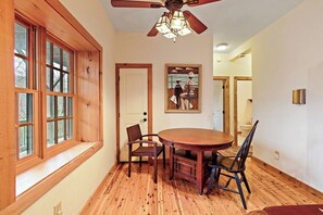 A dining area with a wooden table and chairs, a ceiling fan, and a window with multiple panes. - Game Room, Hot Tub, Fire Pit, Close to Skiing (Seven Devils)
