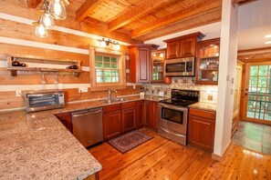 A kitchen with wooden cabinets, a stainless steel oven, a microwave, and a built-in toaster. - Game Room, Hot Tub, Fire Pit, Close to Skiing (Seven Devils)