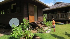 Una cabaña de madera con antena parabólica, un porche y un patio cubierto de césped.