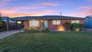 Une maison de plain-pied en briques, dotée d’un porche à l’avant, d’un garage et d’une pelouse bien entretenue.