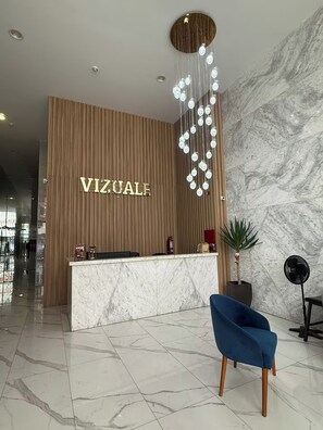 A reception area with a wooden wall, a marble reception desk, and a blue chair. - APT VIZUALE - LINCE (Lima)