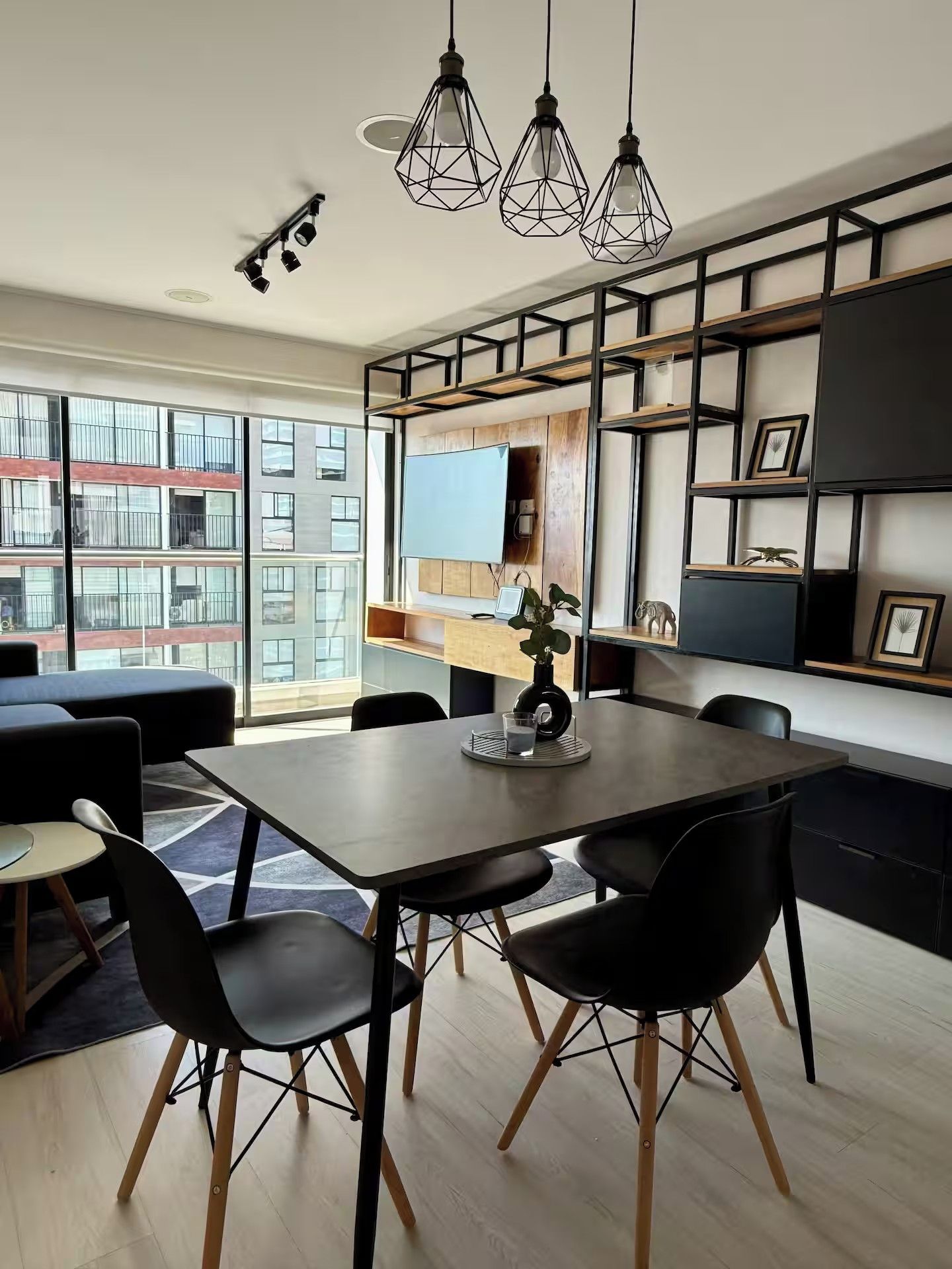 A modern dining area with a large table, black chairs, and pendant lighting.