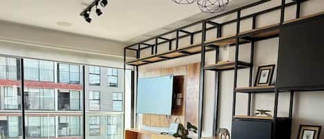 A modern dining area with a large table, black chairs, and pendant lighting.