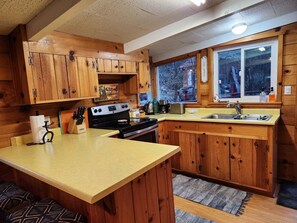 Cocina compacta con gabinetes de madera, una isla central, estufa y ventana con vistas al exterior.