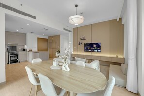 Eine moderne Küche mit Backofen und einem Essbereich mit Holztisch und weißen Stühlen.
