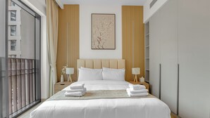 Moderni hotellihuone, jossa on suuri sänky, näköala kaupunkiin ja parveke.