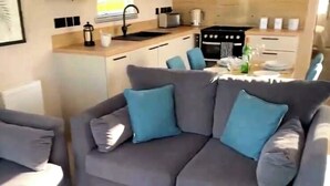Eine moderne Küche mit einem grauen Sofa und einem passenden Sessel, einem Spülbecken und einem Herd.