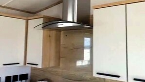 Eine moderne Küche mit weißen Schränken, einer Edelstahl-Dunstabzugshaube und einer Holz Arbeitsplatte.
