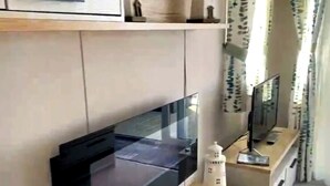 Eine moderne Küche mit Einbauofen, Mikrowelle und zwei Wand-Fernsehern.