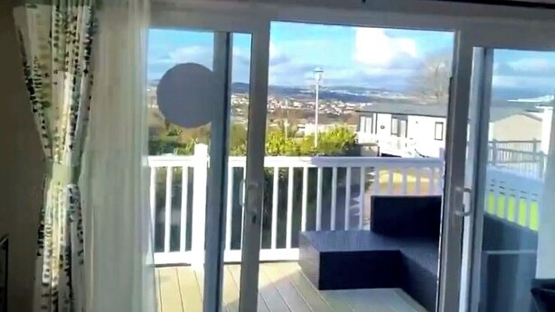 Ein Balkon mit Blick auf eine Wohngegend, einem weißen Geländer und einer Tür zum Innenbereich.