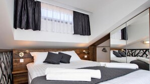 Ein modernes Schlafzimmer mit einem großen Bett, einem Holzkopfstück, einem Spiegel und einem Fenster mit Vorhängen.
