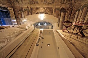A luxurious bedroom with a large bathtub, a bed with white linens, and a decorative chair. - Medici's Abode of Leisure-Next to the station. (Firenze)