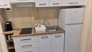 Una cucina compatta con lavello, macchina da caffè e frigorifero.