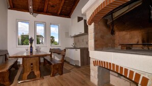 A rustic kitchen with a brick oven, wooden furniture, and large windows. - Adriatic Villa Privlaka - Two bedroom Villa with pool (Privlaka)
