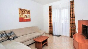Una sala de estar con sofá, mesa de centro, mueble para televisor y cortinas.