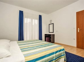 A bedroom with a bed, a wooden door, a small table, and a chair. - Apartments Macolić Rab - One Bedroom Apartment With Balcony (A1) (Rab)