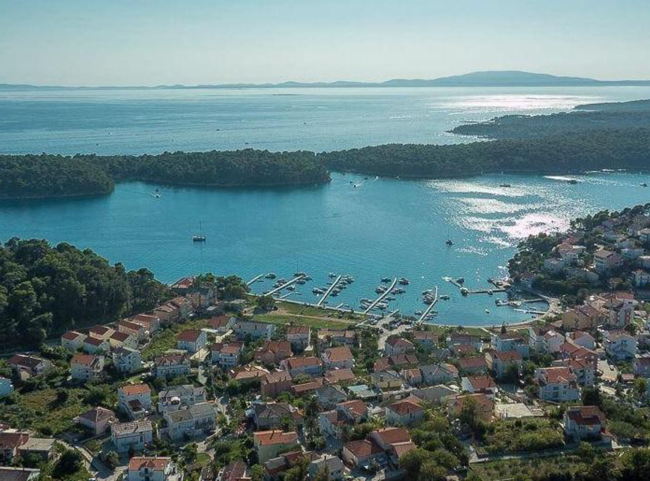 A coastal town with a marina, houses, and a view of the sea.