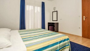 Un dormitorio con una cama, una puerta de madera, una mesita y una silla.