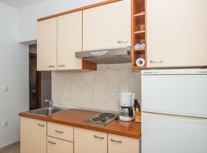 Une cuisine avec des armoires de couleur beige, un plan de travail en bois, un four encastré et une machine à café.